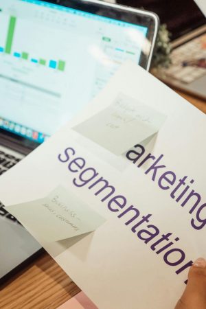 A modern workspace showing hands analyzing marketing data on a laptop and paper documents.